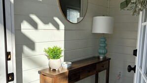 Une console en bois, agrémentée d’un miroir, d’une lampe et d’une plante en pot.