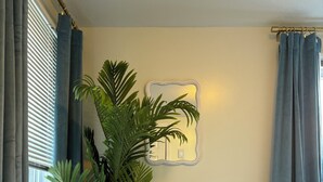 Une chambre à coucher avec un lit, une plante en pot, un miroir et des rideaux.