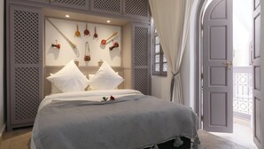 Ein ordentlich bezogenes Bett mit weißen Leinen und einer grauen Decke, eine Wandablage mit Dekoration und eine Tür, die auf einen Außenbalkon führt.