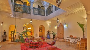 Eine geräumige Lobby mit hoher Decke, aufwendigen Geländern und einer zentralen Sitzecke mit rotem Teppich.