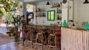 A kitchen with a bar area, wooden stools, and a stone counter. - Sky Studio Apartment 02 Blue Sky Rentals
 (Canacona)