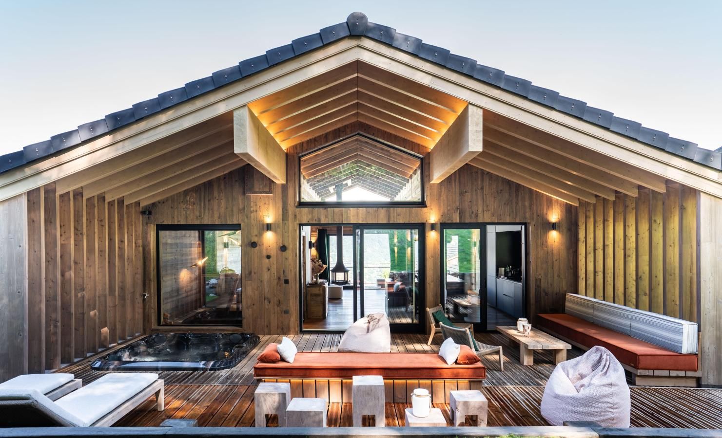 A modern building with a wooden exterior, a hot tub, and a seating area with a view of the outdoors.