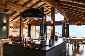 Una cocina moderna con una isla grande, vigas de madera y ventanas amplias que ofrecen vistas a las montañas.