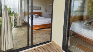 A bedroom with a bed, a ceiling fan, and a view of the outdoors through a glass door. - Charming oceanfront cabin with stunning views, private terrace, and beach access (Santa Marta)