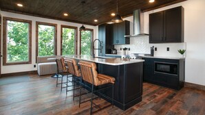 A modern kitchen with a central island, bar stools, and large windows. - 3-Level Luxury Cabin w/ Indoor Pool, Game Loft & Stunning Views (Sevierville)