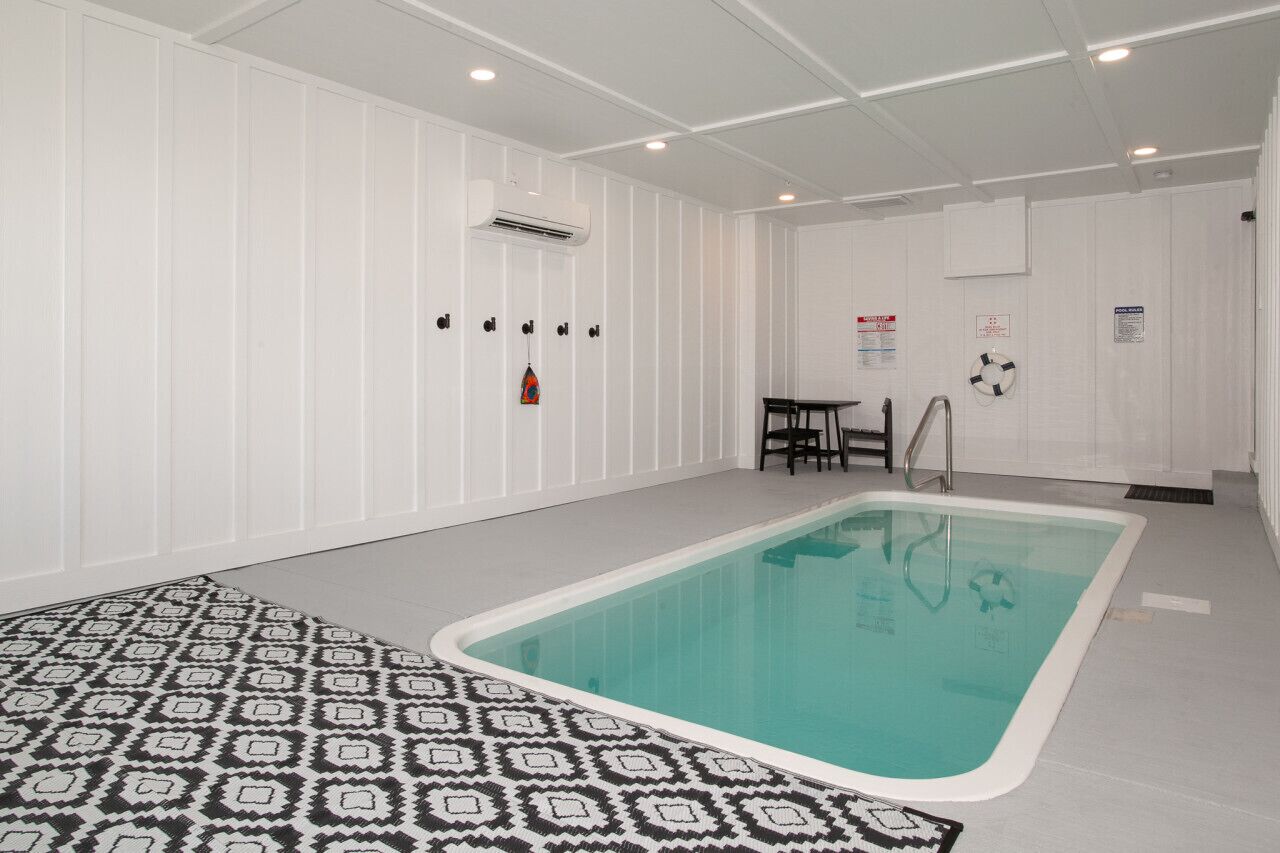 En indendørs swimmingpool med et mønstret gulv og lyse vægge og loftslys.