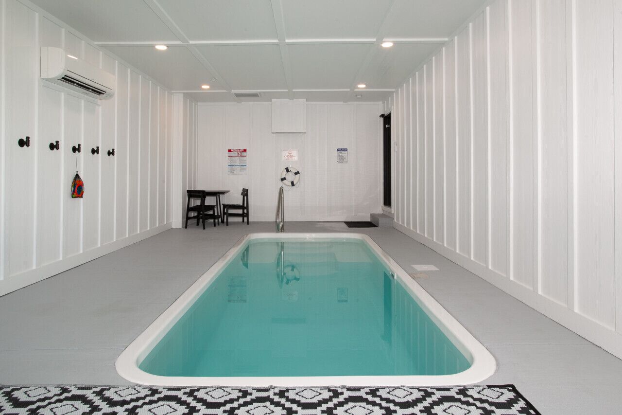 Una piscina con pavimento piastrellato, pareti bianche e un tappeto decorato.