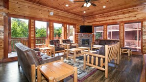 L’intérieur d’un chalet en bois est doté d’une cheminée, de plusieurs coins salon et de grandes fenêtres qui offrent une vue sur l’extérieur.