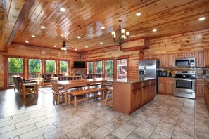A spacious kitchen with wooden cabinets, a large island, and modern appliances. - Rustic-Chic Cabin | Indoor Pool, Game Room & Hot Tub (Sevierville)