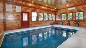 Une cabane en bois avec une piscine, de grandes fenêtres et une porte rouge.