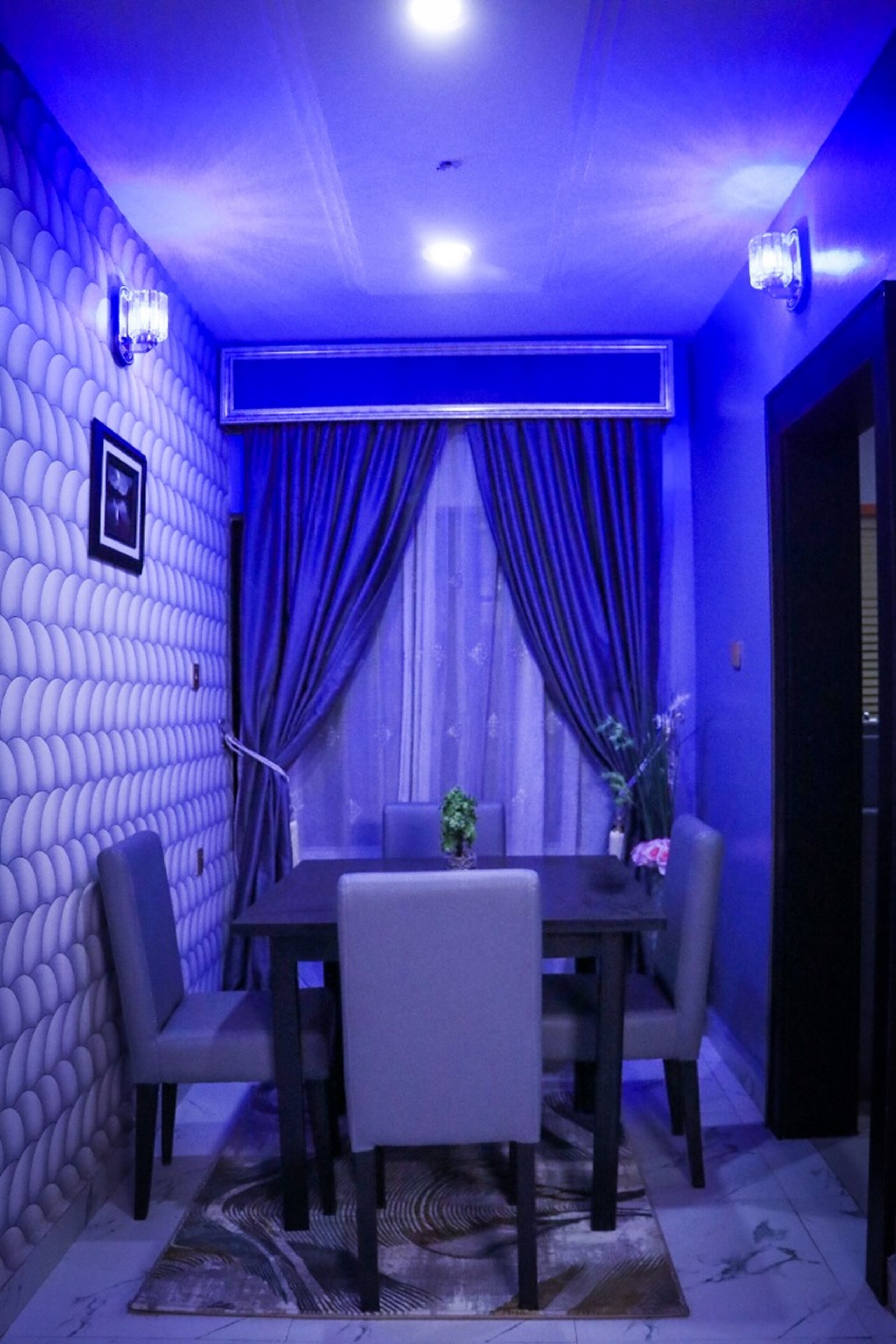 A dining area with a table and chairs, a patterned wall, and a window with curtains.