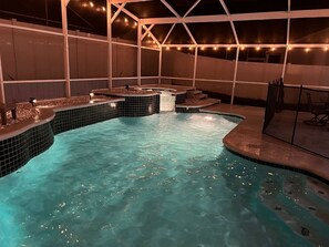 An indoor swimming pool with a tiled edge, a hot tub, and a seating area with a pergola overhead. - Charming 3-bedroom house with WiFi and AC in Kissimmee (Kissimmee)