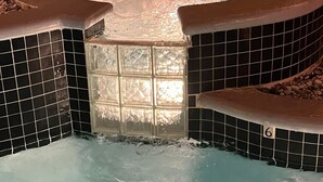 Un jacuzzi con interior de azulejos, desagüe central y un borde revestido de azulejos.