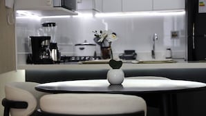 A modern kitchen with a white countertop, a coffee maker, and a vase with white flowers. - Beautiful Apartment Miraflores (Miraflores)
