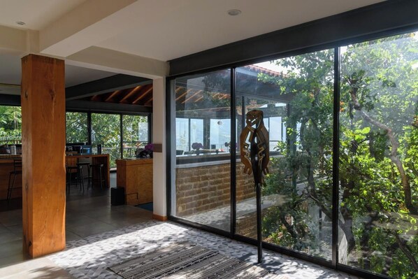 A modern interior with large glass doors leading to an outdoor area, a wooden column, and a bar area.