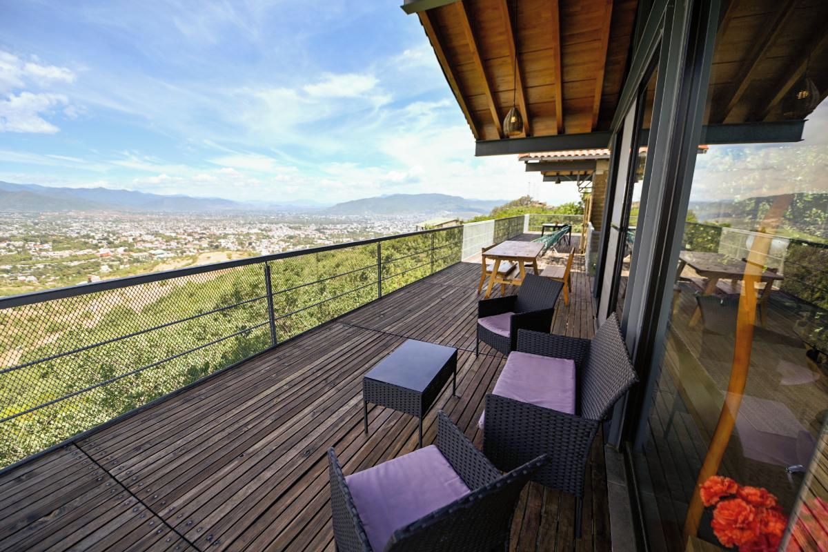 A wooden deck with outdoor furniture and a view of a cityscape.