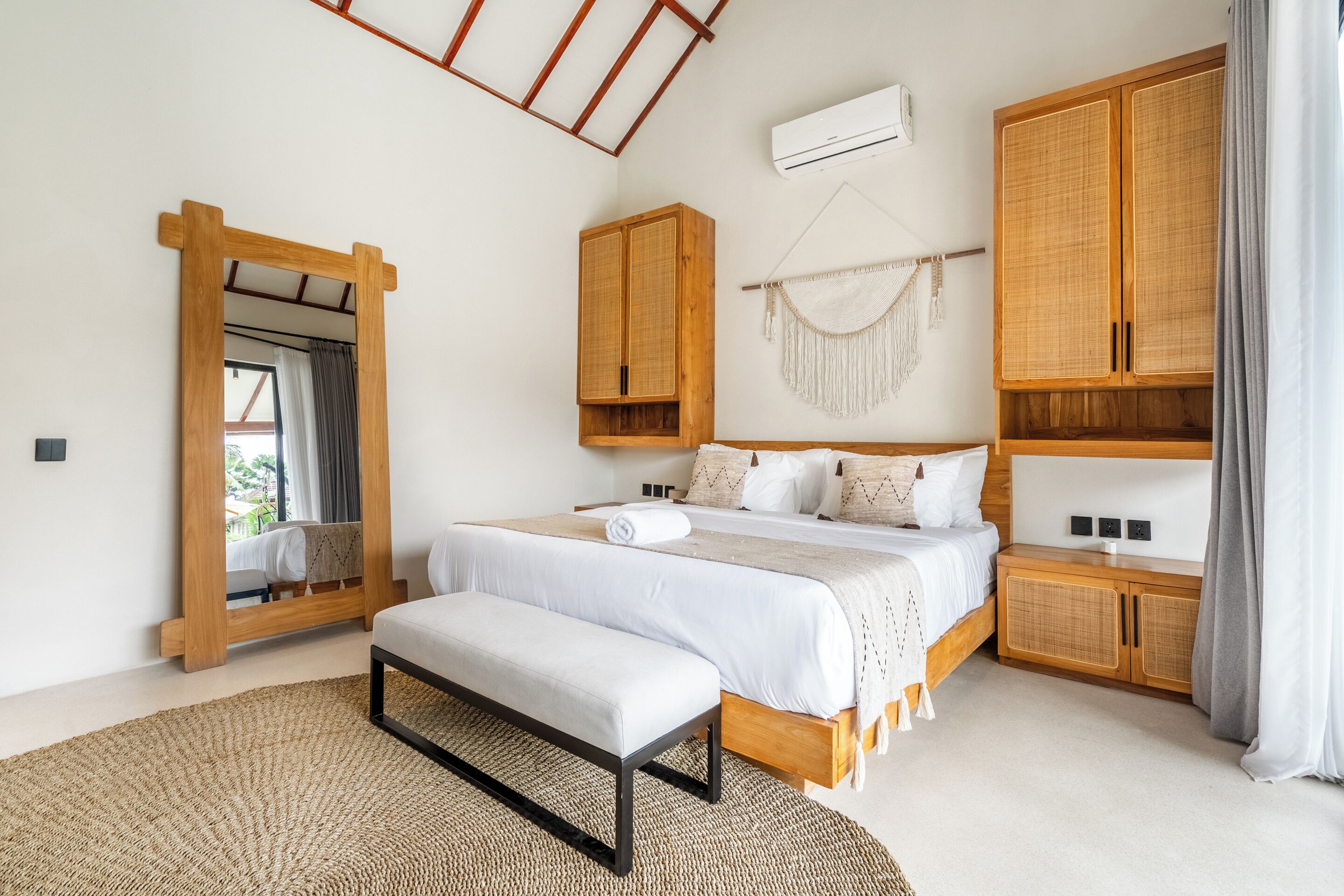 A bedroom with a large bed, wooden wardrobe, and a mirror.