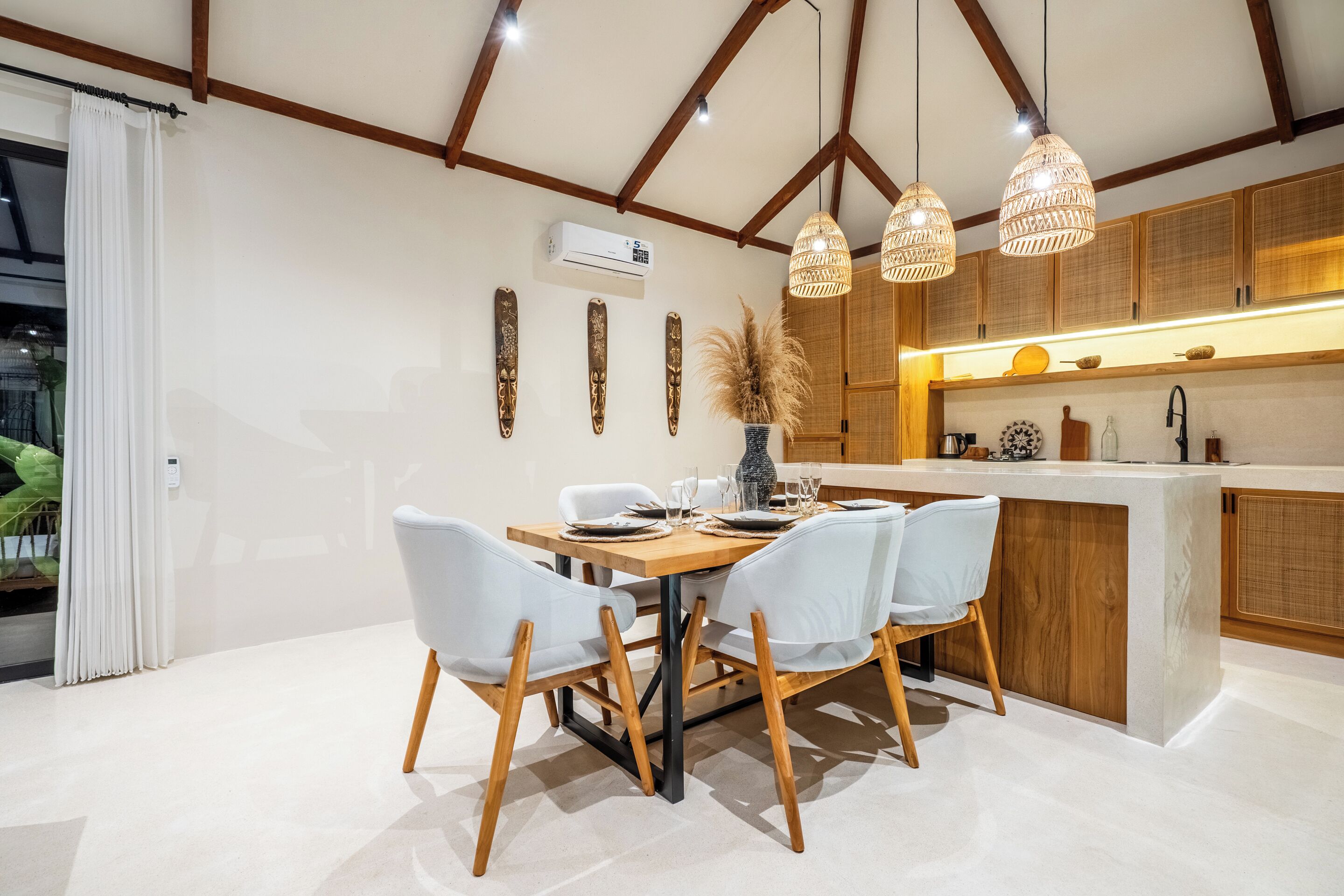 A modern dining area with a wooden table, white chairs, and pendant lights.