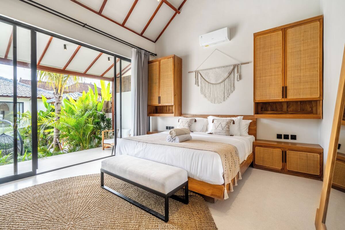 Un dormitorio moderno con una cama grande, armarios de madera y vistas a zonas verdes.