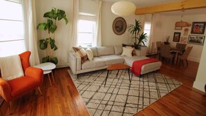 A living room with a sofa, a coffee table, and a dining area with chairs and a table.