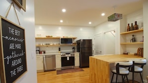 A modern kitchen with white cabinets, a wooden island, and bar stools.