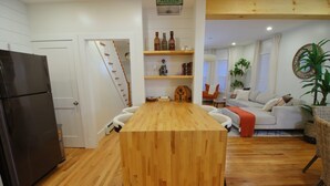 A modern kitchen with a wooden island, white cabinetry, and a black refrigerator.