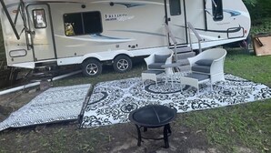 Ein Wohnmobil mit überdachtem Wohnbereich, einer Essecke und einem gemusterten Teppich.
