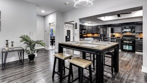 Une cuisine moderne avec un plancher en bois foncé, un îlot central doté de tabourets et des appareils électroménagers en acier inoxydable.