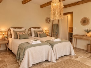 A bedroom with a double bed, two bedside tables, a hanging light fixture, and a mirror on the wall.