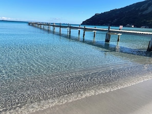 A pier extending into clear blue water with a sandy beach and a mountainous backdrop. - Modern sheep barn, 5 minutes from the beach and amenities in PORTO VECCHIO (PORTO VECCHIO)