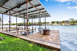 A wooden dock extending into a calm lake, with a covered seating area and a fire pit. - Beautiful Lakefront Cabin Something For Everyone (New Braunfels)