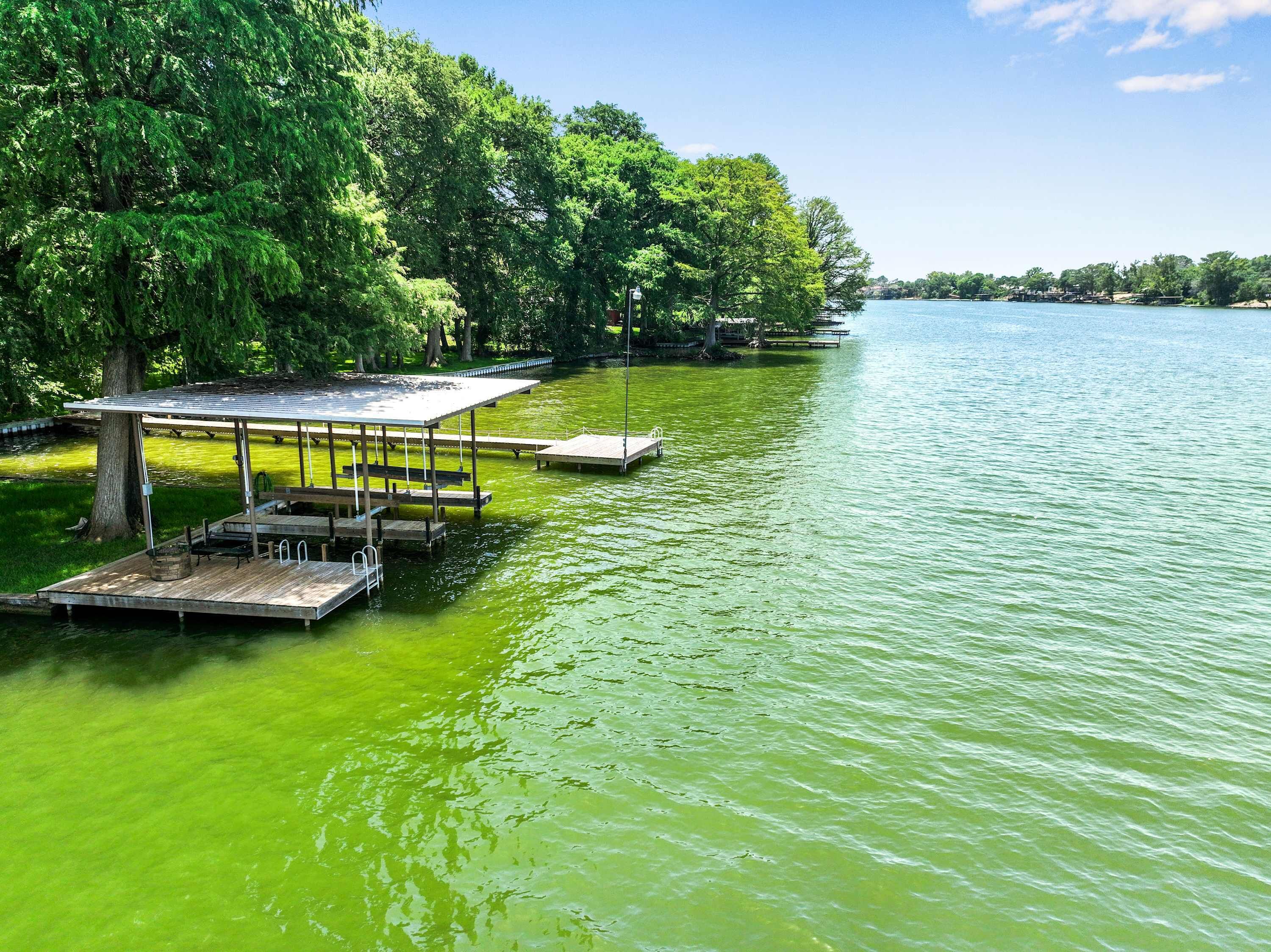 A lakeside dock with a covered seating area and a wooden pier extending into the water.