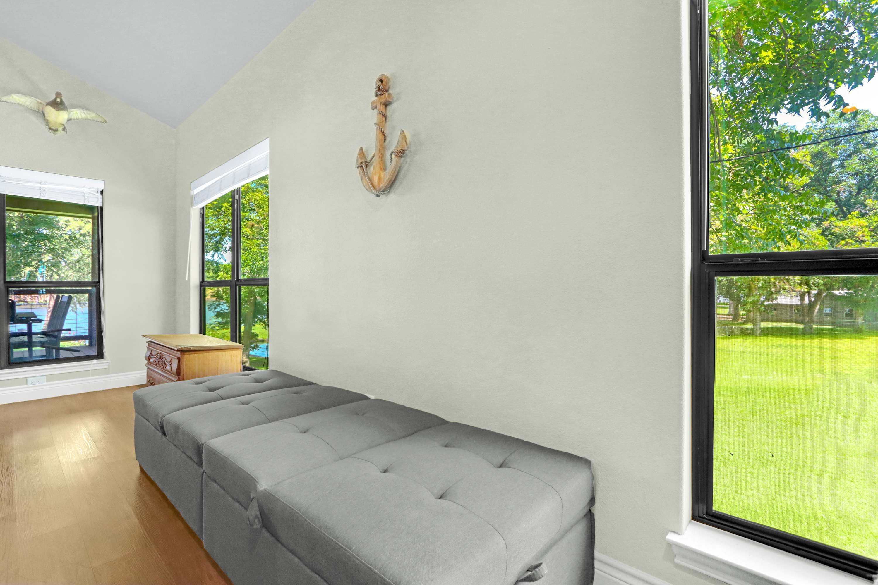 A room with a grey sofa, wooden side table, and a wall-mounted anchor decoration.