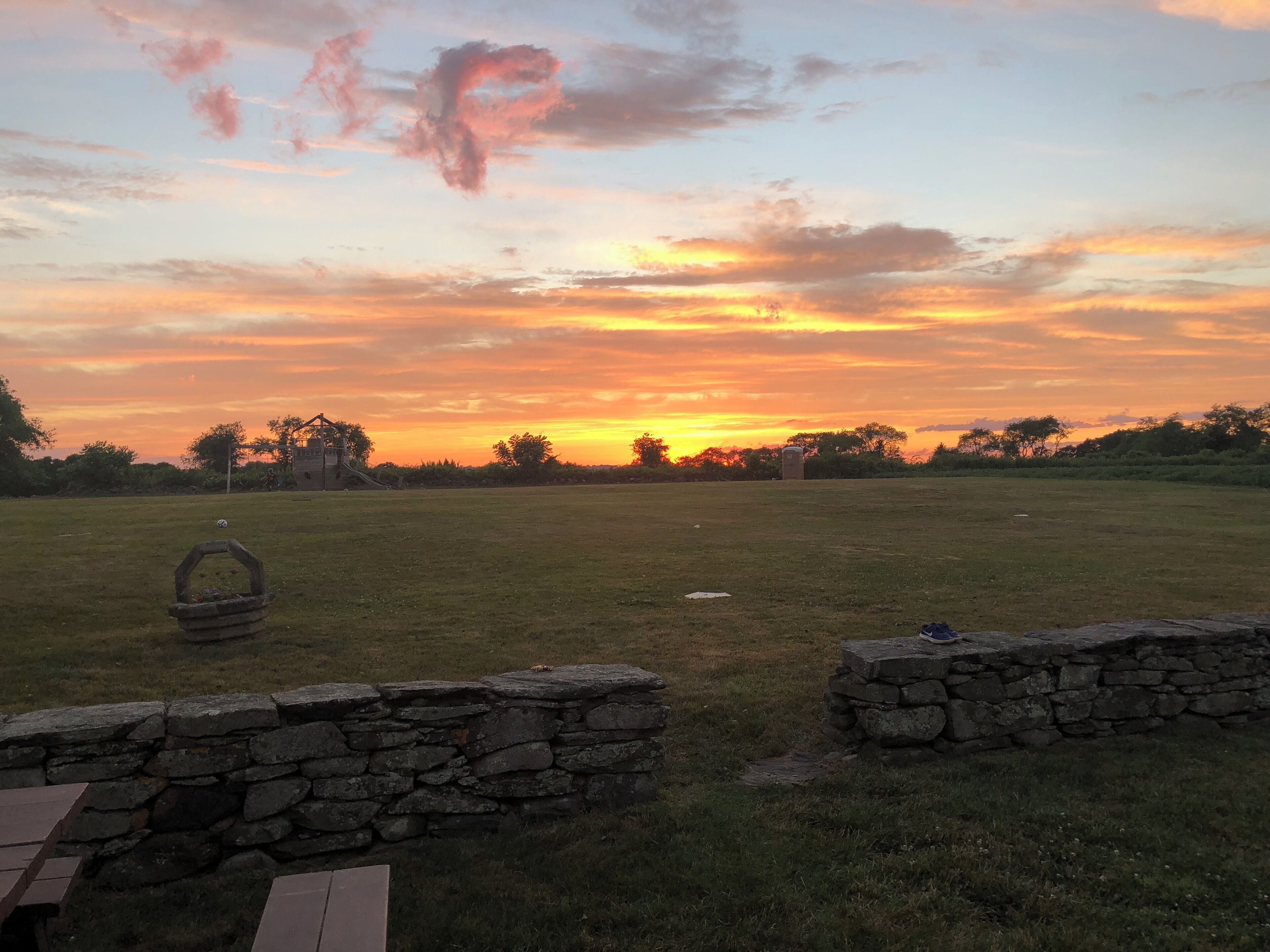 A grassy field with stone walls and a wooden bench.