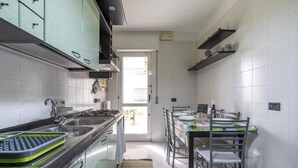 A modern kitchen with a dining area, featuring a stainless steel sink, a built-in oven, and a dining table with chairs. - Green house (Monopoli)