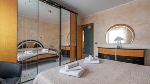 A hotel room with a bed, a mirror, a bedside table, and a sliding glass door leading to a balcony. - Green house (Monopoli)
