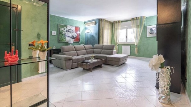 A living room with a sectional sofa, a coffee table, and a glass partition. - Green house (Monopoli)