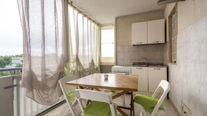 A small kitchen with a dining table and chairs, a window with curtains, and a view of the outside. - Green house (Monopoli)