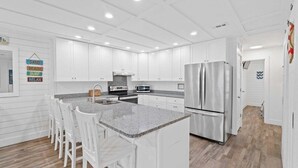 Una cocina moderna con armarios blancos, una isla de encimera de granito y electrodomésticos de acero inoxidable.