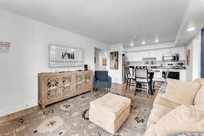 Una sala de estar moderna con un sofá color beige, un sillón azul y un mueble de madera con detalles decorativos.