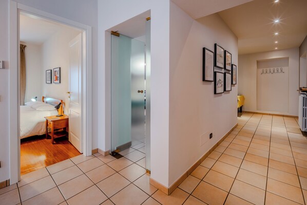 Habitación de hotel con cama, mesita de noche y baño visible a través de una puerta de cristal.