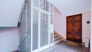 Eine Treppe mit Metallgeländer, einer Holztür und einem Fliesenboden.
