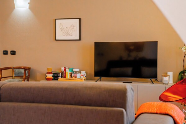 A living room with a flat-screen TV, a framed picture, a bookshelf, and a red chair.