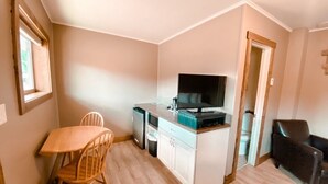 Eine kompakte Küche mit Esstisch und Stühlen, einem kleinen Kühlschrank und einem Fernseher.