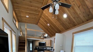 A spacious living area with a sofa, a television, wooden flooring, and a ceiling fan. - Relaxing Getaway in our Cottage at Lodges of Oak Creek! (Oak Creek)