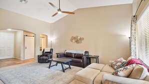 A spacious living room with a ceiling fan, a sofa, a coffee table, and a patterned rug.