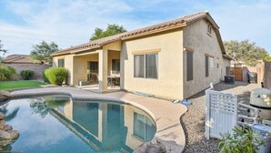 A two-story house with a swimming pool, a patio, and a fenced backyard.