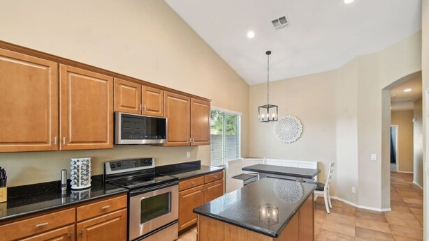 A modern kitchen with wooden cabinets, stainless steel appliances, and a large island.