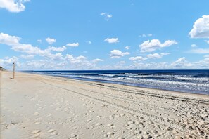 A sandy beach with footprints leading to the ocean. - Seaside Haven - Sleep 13 (Surf City)
