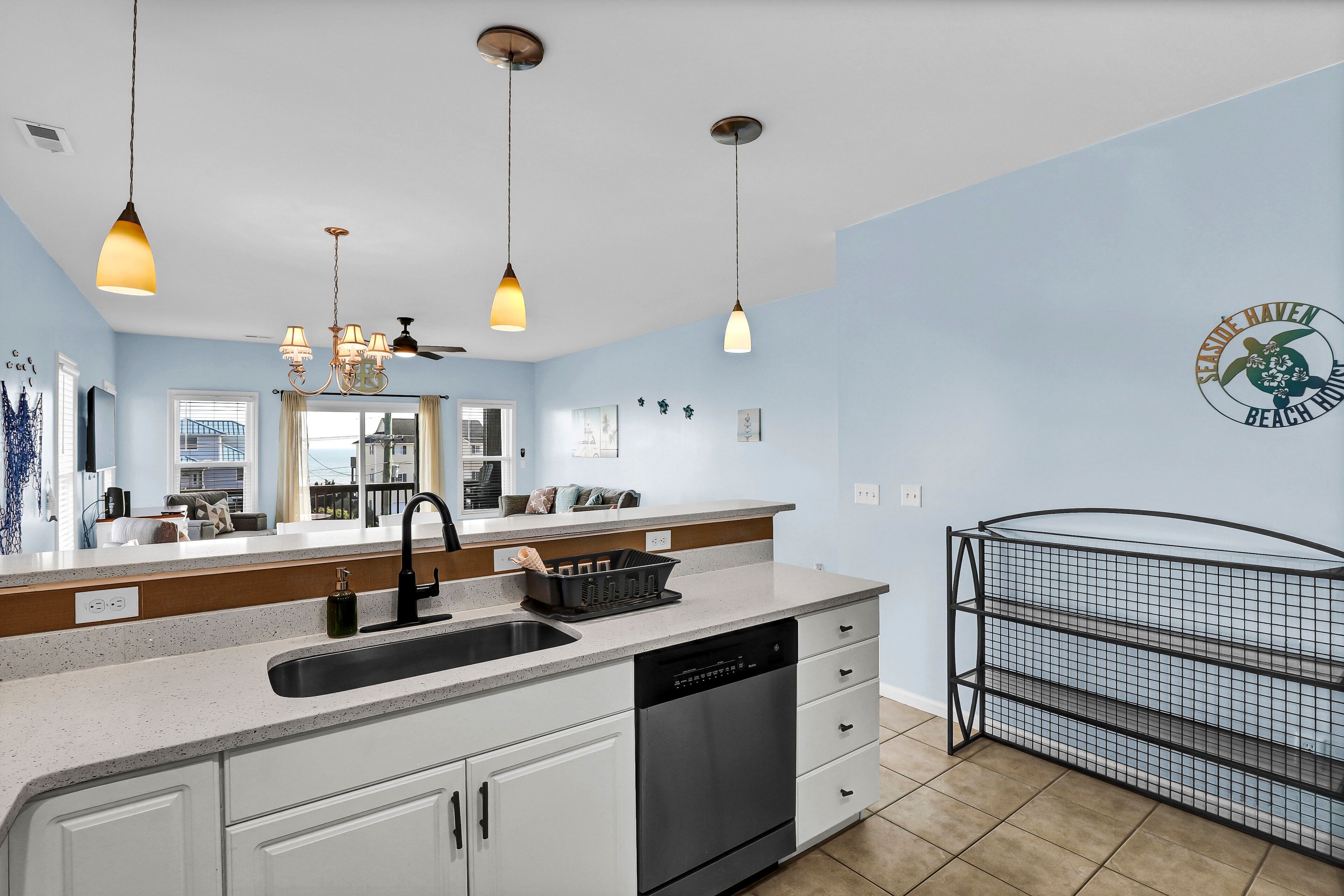 A modern kitchen with a dishwasher, a sink, and a black metal shelf unit.